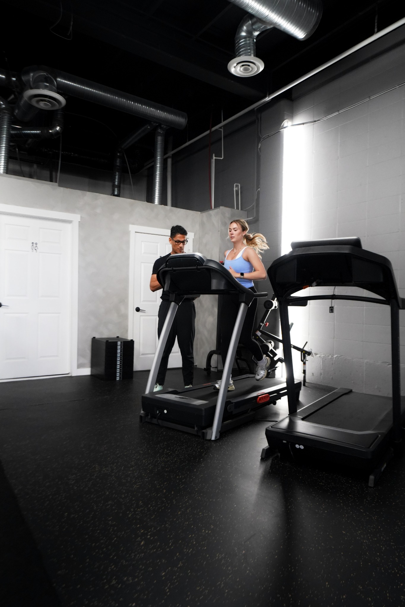 A practitioner observing a runner on a treadmill during a running assessment at REVIVELAB