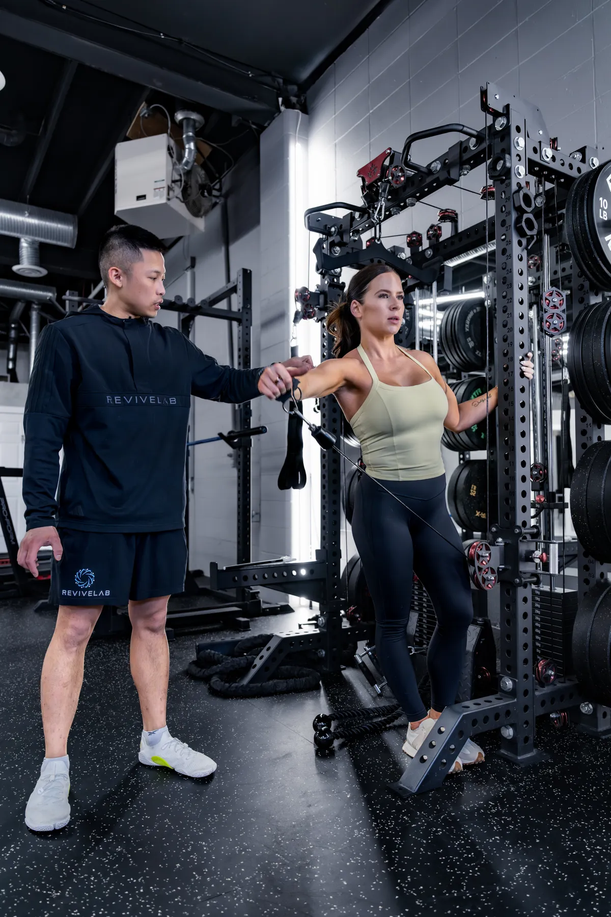 REVIVELAB coach guiding a client through a cable exercise in the private Bridgeland gym